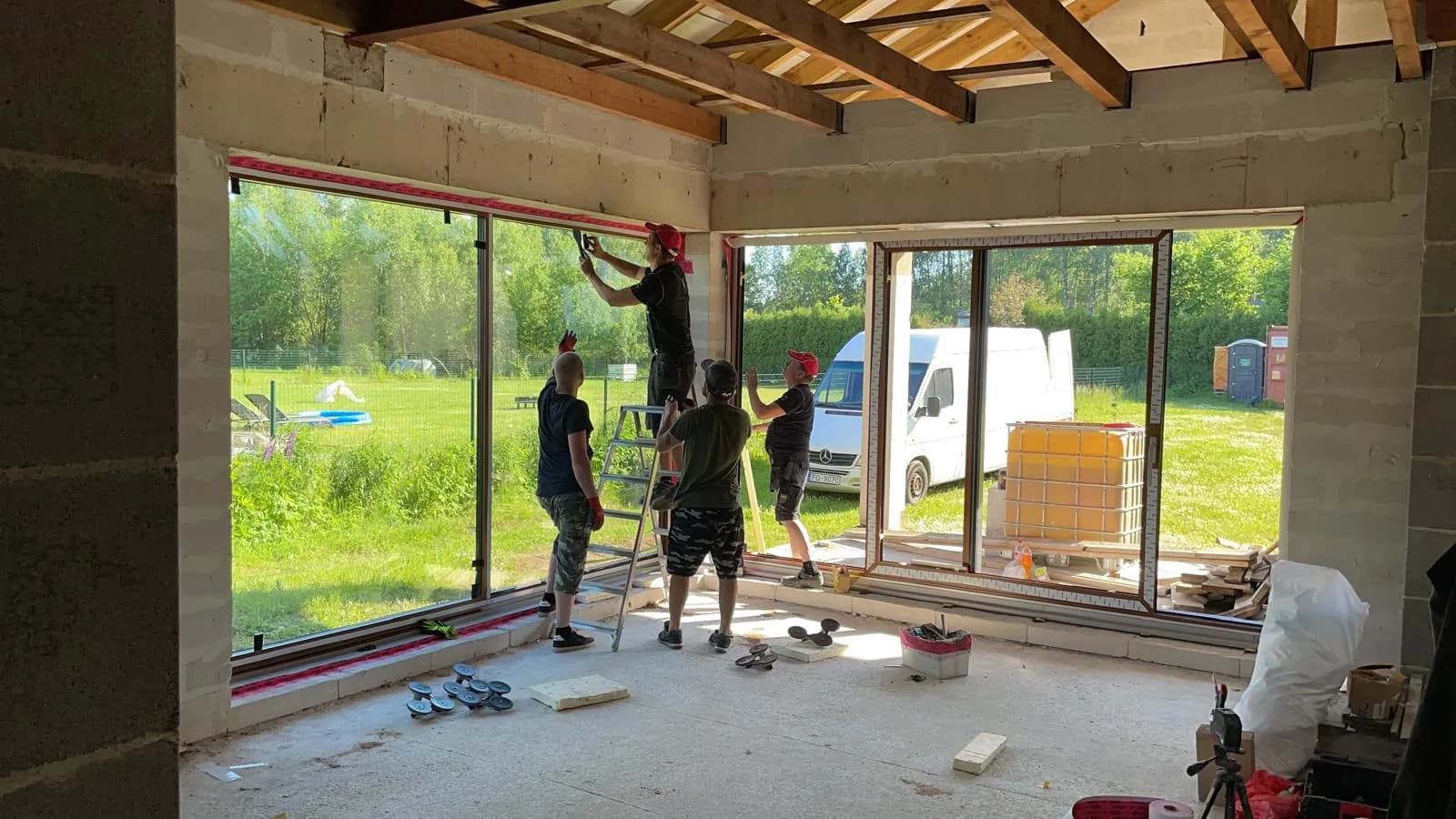 Montāžas komanda uzstāda stūra stiklojumu jaunbūvē